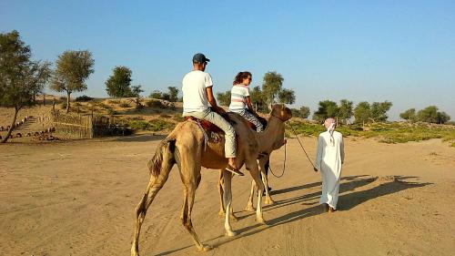 a man and a woman riding on a camel with a man at Al Reem Desert Camp in Jalan Bani Buhassan