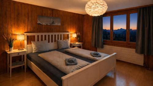 a bedroom with a large bed and a chandelier at CLOUD No3 Schweizer Chalet-Wohnung mit zentraler Klimaanlage in Matten