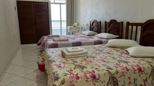 two beds sitting next to each other in a room at Hotel Polonini in Piúma