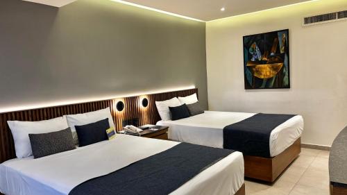 a hotel room with two beds and a chair at Hotel Guadalajara Plaza Ejecutivo in Guadalajara