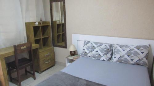 a bedroom with a bed and a dresser and a mirror at Edícula Recanto das Palmeiras in Uberaba