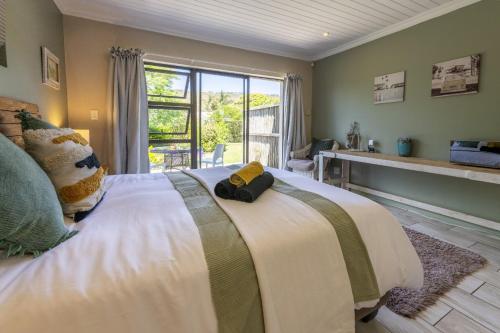 a bedroom with a large bed with a large window at Garden View Studio in Plettenberg Bay
