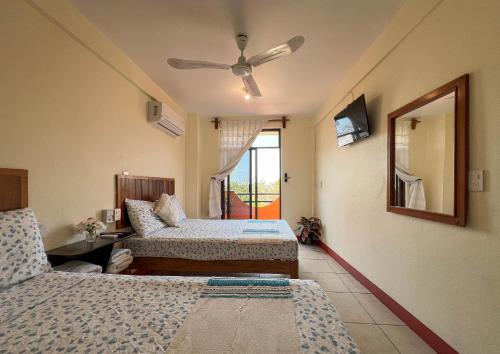 a bedroom with two beds and a ceiling fan at Bacanda Hotel in Puerto Escondido