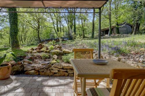 a patio with a table and chairs and a stone wall at Les totems de Grésigne in Penne