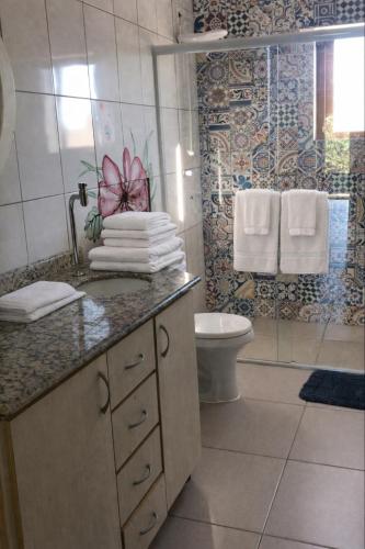 a bathroom with a sink and a toilet and towels at Suites Guarda do Embau in Palhoça