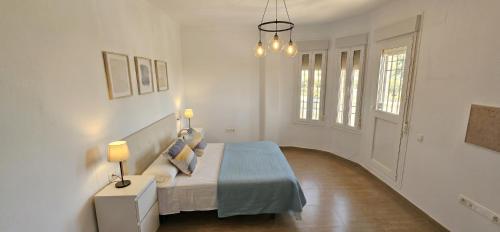 a white bedroom with a bed and a chandelier at Casa Rural Los Gaspares in La Carlota