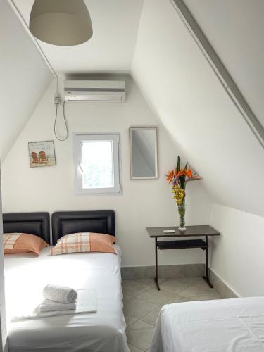a attic bedroom with two beds and a table at Apartments and Bungalows Mimoza Baošići in Herceg-Novi