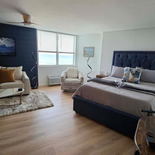 a bedroom with a large bed and a chair at Cuddle's Comfort & OCEAN in Daytona Beach