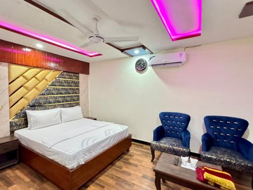 a bedroom with a bed and two blue chairs at Rose Family Lodges in Islamabad