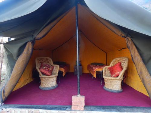 a tent with two chairs and a table in it at Dhanaulti Camp Homes Retreat in Dhanaulti
