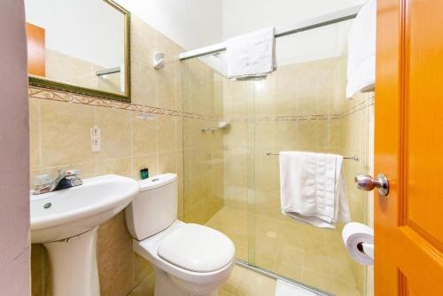 a bathroom with a toilet and a sink and a shower at Hotel Optimum in Pereira