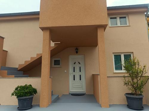 a house with a white door and two potted plants at Cozy apartments with sea view in Novi Vinodolski