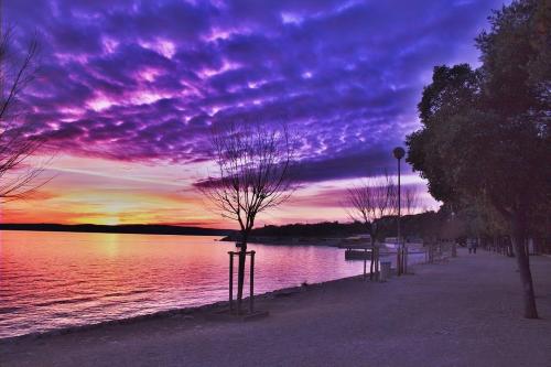 a sunset over a body of water with trees at Cozy apartments with sea view in Novi Vinodolski