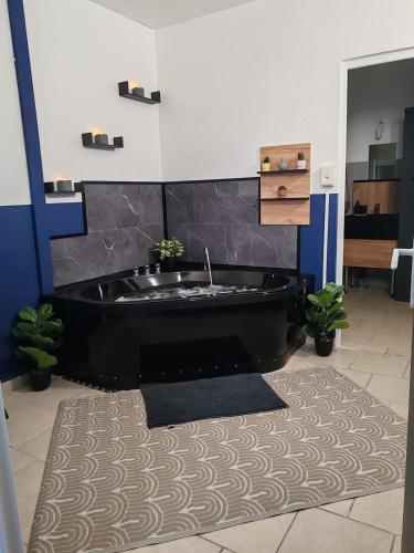 Eine schwarze Badewanne in einem Badezimmer mit einem Teppich in der Unterkunft Le Maley in Dunkerque