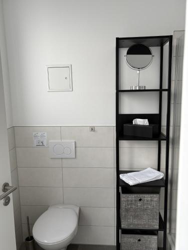 a bathroom with a toilet and a mirror on a shelf at 247 Reside - Apartment SZ3 in Straubing