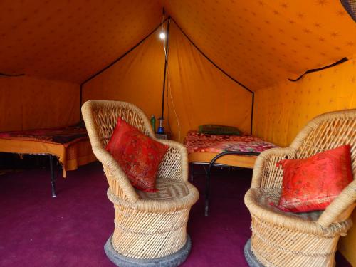 two wicker chairs and a bed in a tent at Dhanaulti Camp Homes Retreat in Dhanaulti