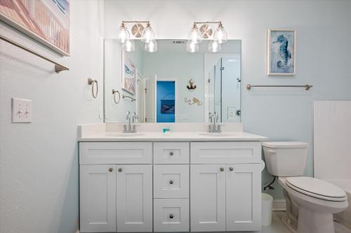 a white bathroom with a sink and a toilet at Let's get Beachy! in Bolivar Peninsula