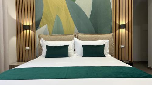 a bedroom with a large bed with two green pillows at COLIBRI Rooms in Agrigento