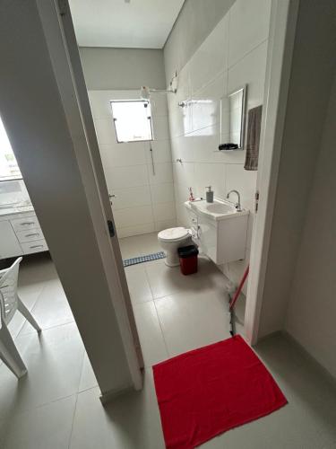 a bathroom with a toilet and a sink and a red rug at 05 Studios centro,proximo a rodoviaria-itapeva sp in Itapeva