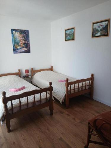 two twin beds in a room with wooden floors at Maja Apartman in Igalo