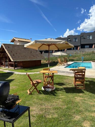 a picnic table with an umbrella next to a pool at Chalés Champion Capitolio in Capitólio