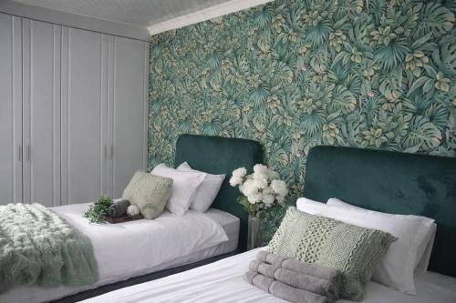 a bedroom with two beds and a floral wallpaper at Maun Fortress in Maun Airport