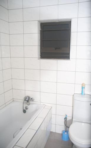 a bathroom with a tub and a toilet and a window at Maun Fortress in Maun Airport