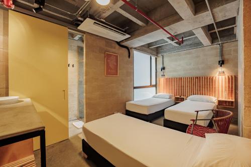 The Somos S Hotel في ميديلين: غرفة بها ثلاثة أسرّة وطاولة