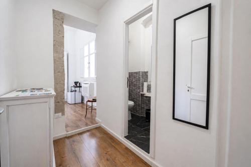 a white room with a mirror and a bathroom at Sa Costixedda Rooms in Cagliari