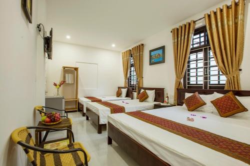 a hotel room with four beds and a chair at Golden Bee Homestay in Hoi An