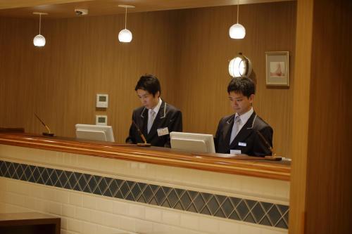 two men in suits sitting at a reception desk at Hotel Monte Hermana Kobe Amalie in Kobe