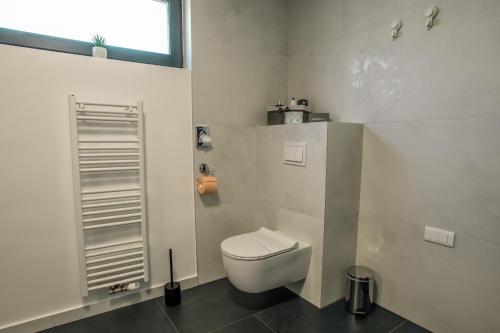 a bathroom with a white toilet and a window at UrbanApartment5 in Čakovec