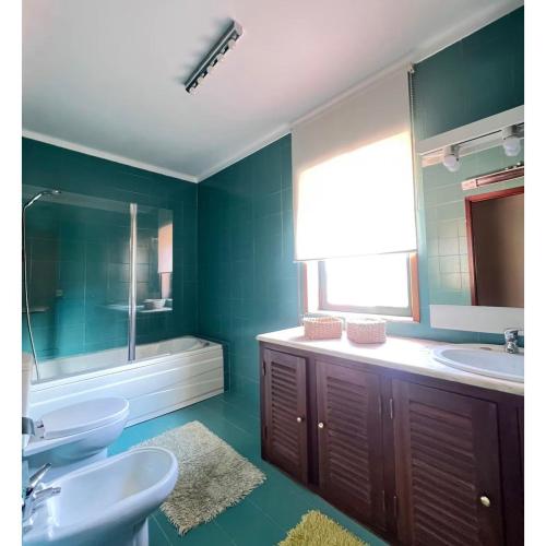 a green bathroom with two sinks and a mirror at Casa SAL in Esposende