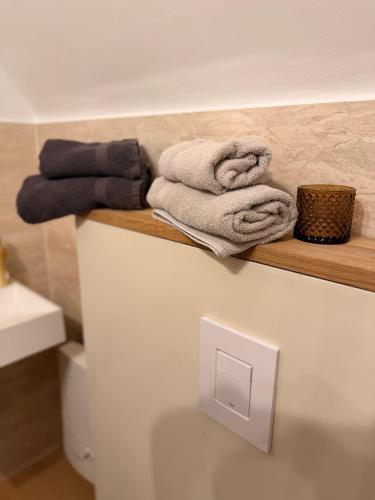 a bathroom with towels on a wooden shelf above a toilet at LevelUp Comfort in Koblenz