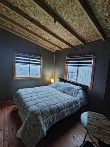 a bedroom with a large bed and two windows at Casa kumey in Puerto Varas