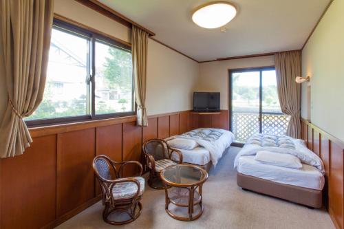 a room with two beds and chairs and a tv at Schole Hakuba in Hakuba