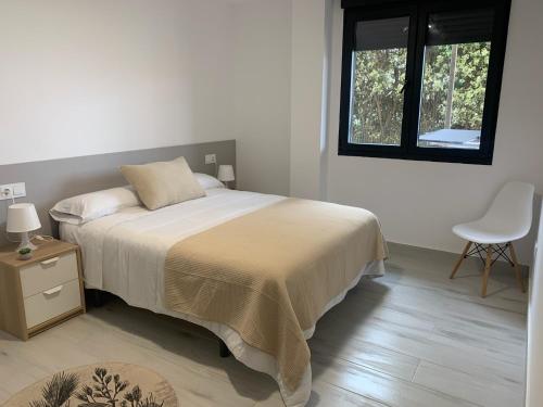 a bedroom with a bed and a chair and a window at Canelas 22 in Sanxenxo