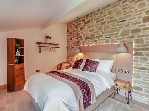 a bedroom with a large bed and a brick wall at 1 Bed in Shepton Mallet oc-94296 in Pilton