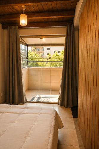 a bedroom with a bed and a large window at Refúgio com Varanda, Wi-Fi Rápido, 450m da Praia, seu Cantinho em BC in Balneário Camboriú