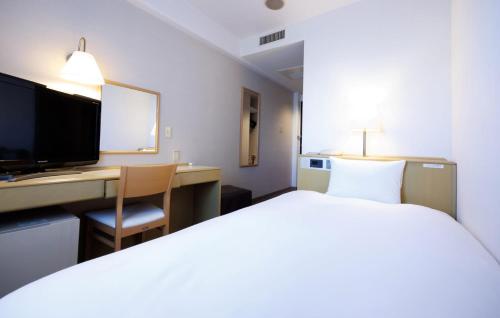 a hotel room with a bed and a desk and a television at Court Hotel Mito in Mito