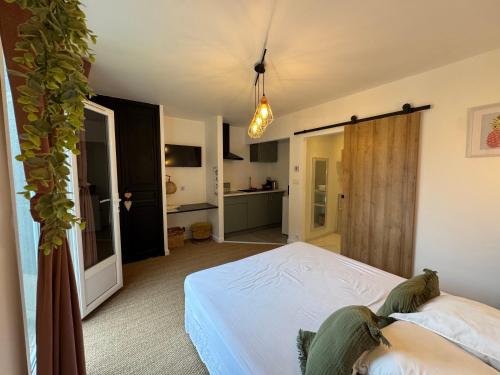 a bedroom with a white bed and a kitchen at La tanière studio in Les Brugassières