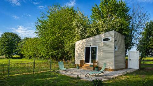 a small shed with two chairs and a fence at Cabane insolite en pleine nature - La cabane de Dim in Grumesnil
