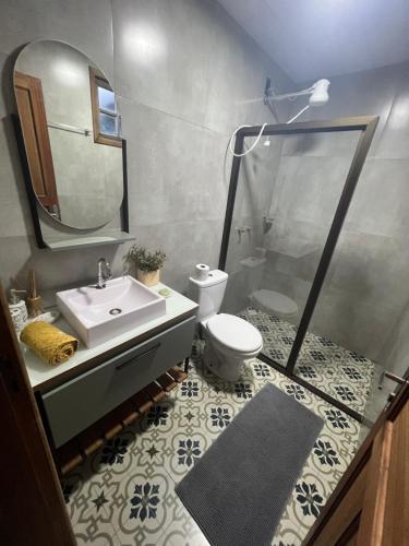 a bathroom with a sink and a toilet and a mirror at Bangalo Bela Vista in Caparaó Velho