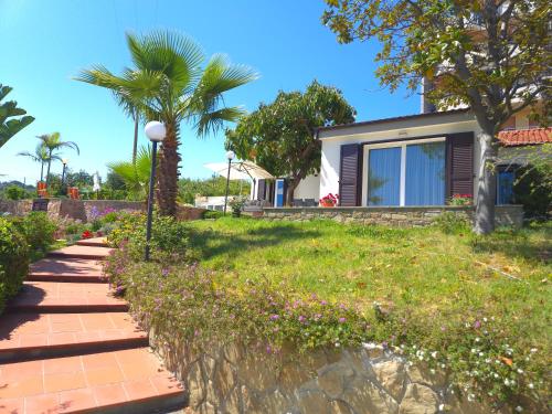 a house with a palm tree and a sidewalk at Oasis Villa - Sea View Pool, Sanremo in Sanremo