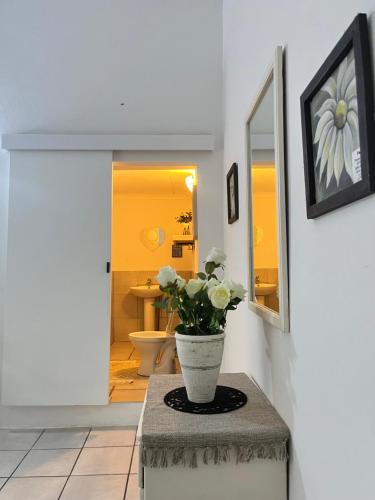 a vase with flowers on a table in a bathroom at Nandina Self Catering in Hazyview