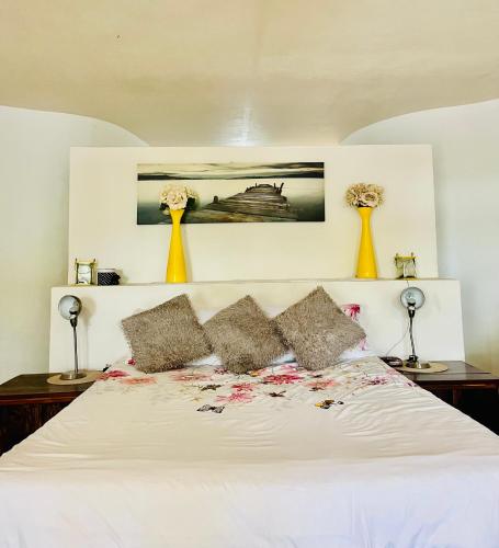 a bedroom with a white bed with two yellow vases at Nandina Self Catering in Hazyview