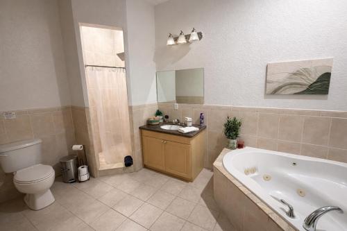 a bathroom with a tub and a toilet and a sink at Peaceful Inn at Deerfield Beach Boca Raton in Deerfield Beach