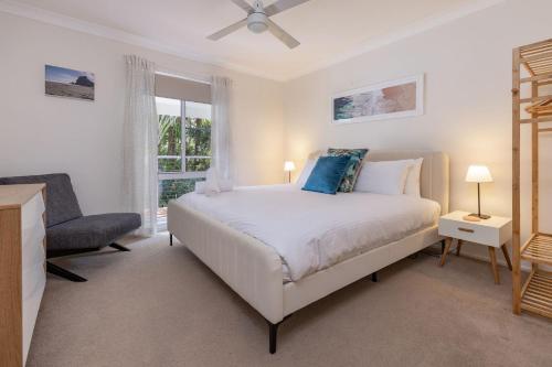 a bedroom with a bed and a chair and a window at Boo's Place in Blueys Beach