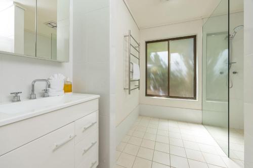 a white bathroom with a sink and a shower at Boo's Place in Blueys Beach