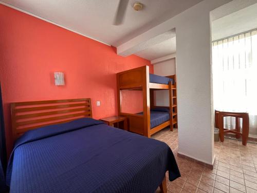 a bedroom with a blue bed and a red wall at Hotel Soberanis in Cancún
